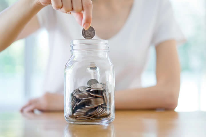 Woman Dropping Coins Into Jar