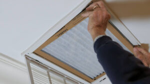 A man replacing an HVAC air filter.