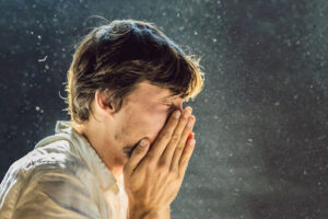 A man sneezing due to dust.