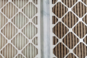 A clean HVAC air filter next to a dirty filter.